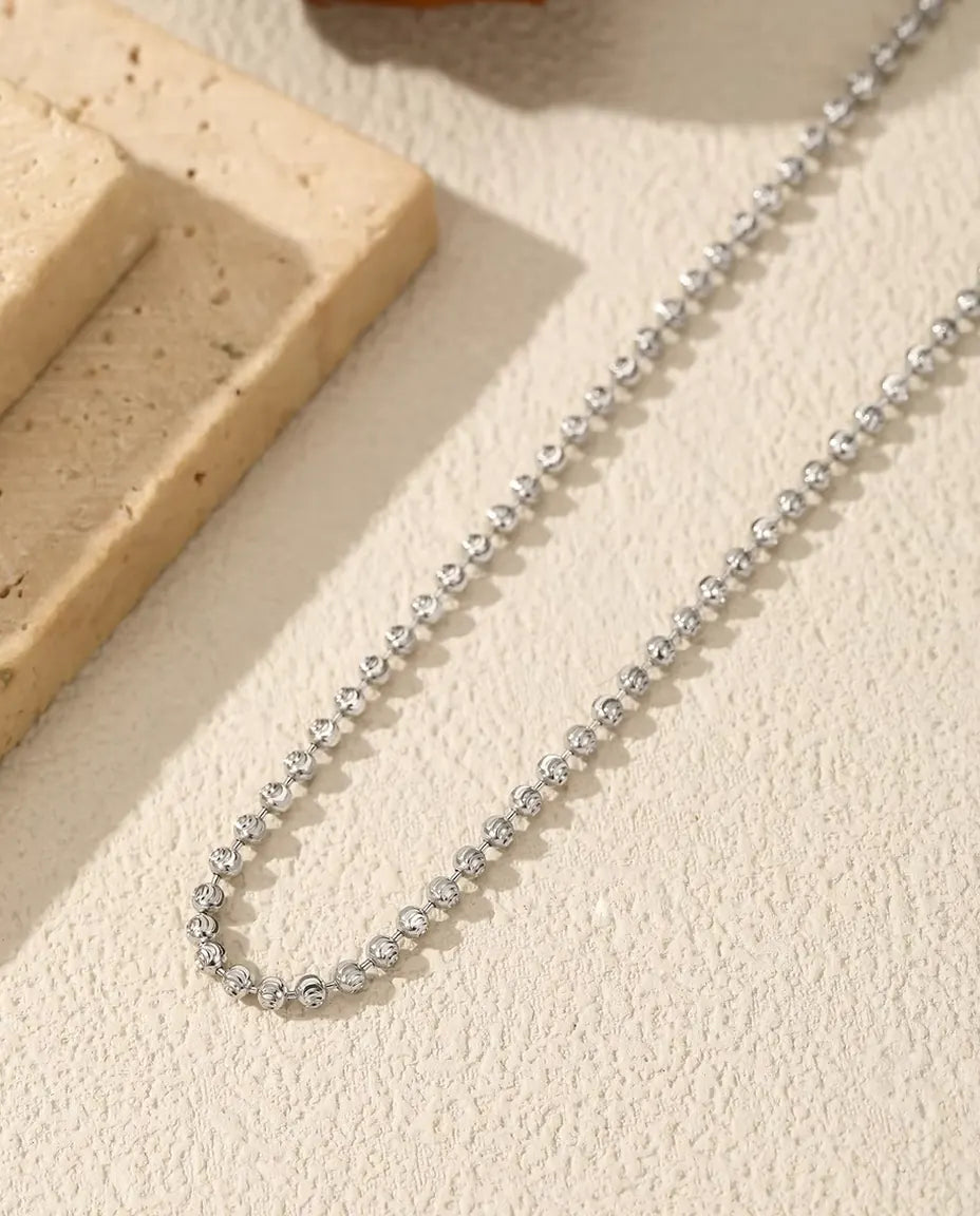 Kugelkette aus 925 Sterlingsilber - über helle Fläche neben einer Travertinplatte gelegt