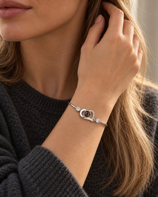 Frau mit der Hand im Haar trägt das silberfarbene Armband mit offenem Herz und Bild im Stein