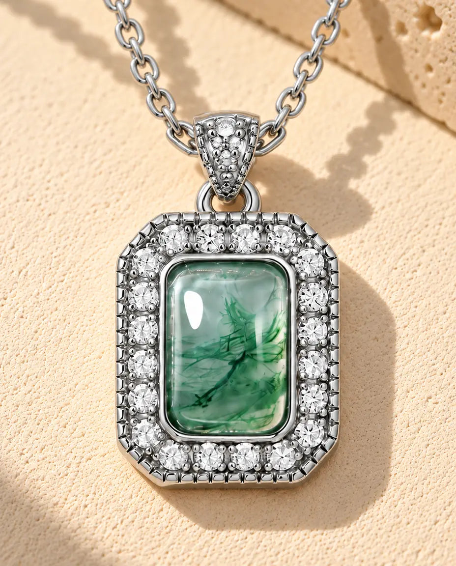 Moosachat Halo Kette aus 925 Sterlingsilber - auf heller Strukturfläche neben einem Travertinblock liegend