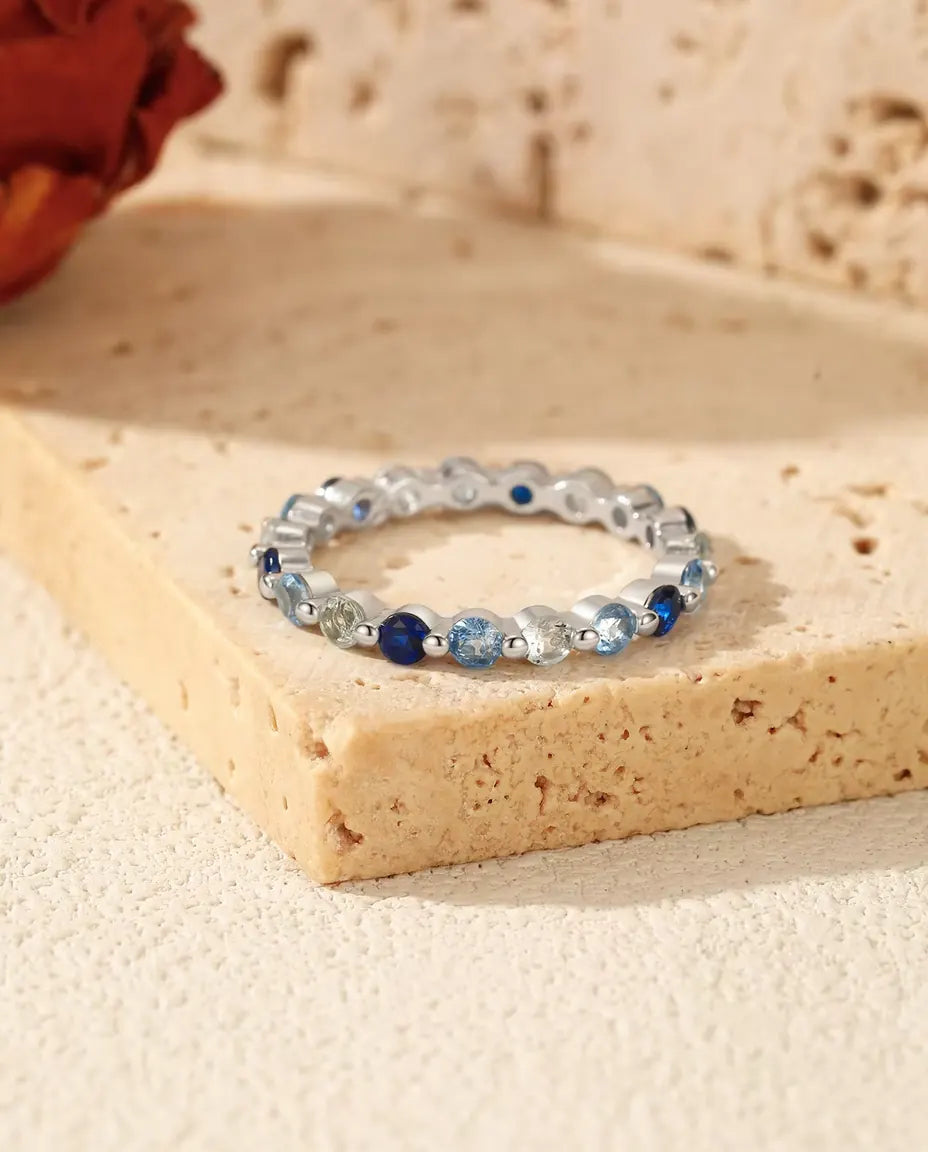 Memoire Ring mit blauen Zirkonia aus 925 Sterlingsilber - auf einem Travertinblock liegend