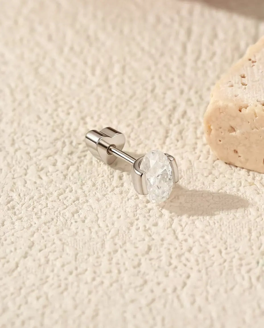 Ovale Moissanit Ohrstecker mit Seitenleisten aus 925 Sterlingsilber - seitlich liegend auf heller Strukturfläche, herzförmiger Verschluss auf dem Stift
