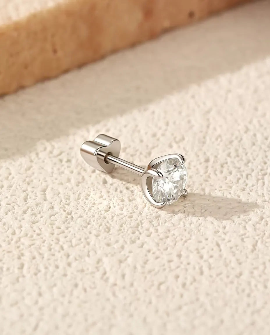 Runde Moissanit Solitär-Ohrstecker mit vier Krappen aus 925 Sterlingsilber - seitlich liegend auf heller Strukturfläche, herzförmiger Verschluss auf dem Stift