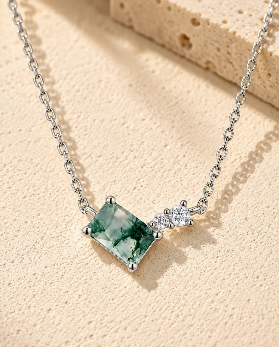 Moosachat Kette aus 925 Sterlingsilber - auf heller Strukturfläche neben einem Travertinblock liegend