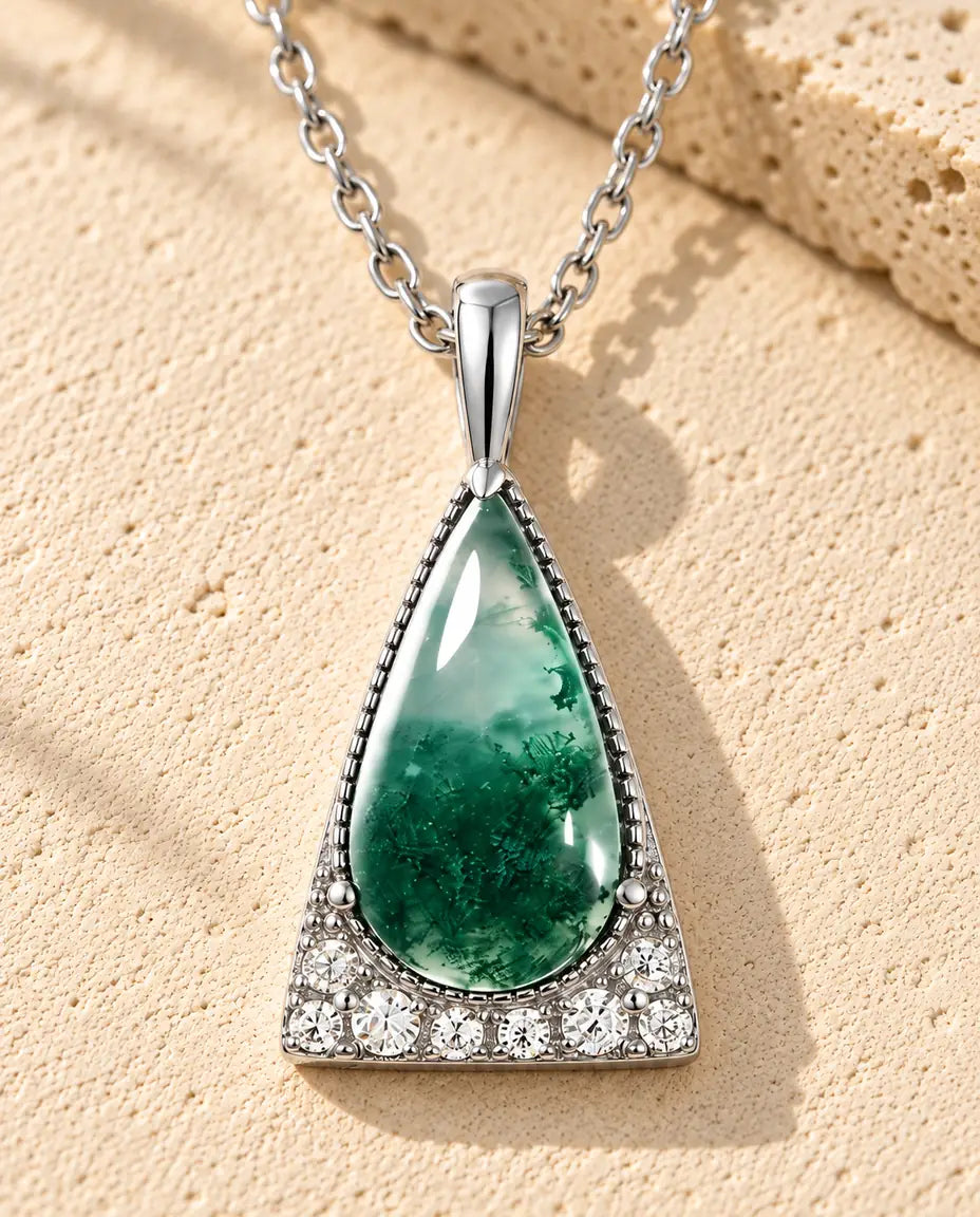 Moosachat Dreieck Kette aus 925 Sterlingsilber - auf heller Strukturfläche neben einem Travertinblock liegend