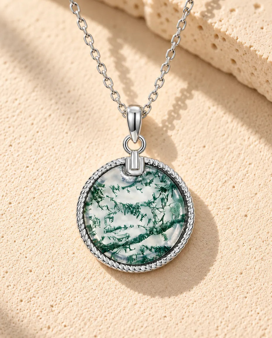 Runde Moosachat Medaillon Kette aus 925 Sterlingsilber - auf heller Strukturfläche neben einem Travertinblock liegend