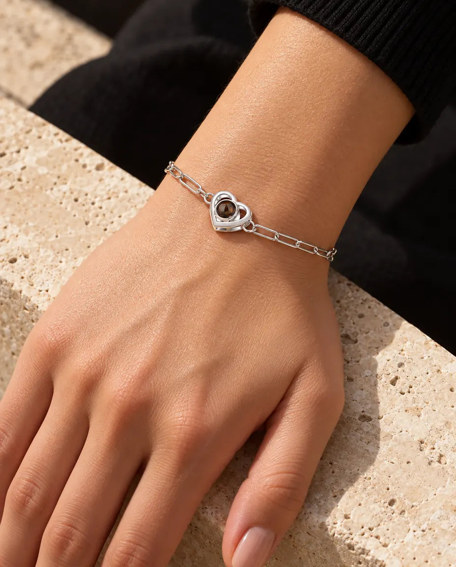 Frau trägt das silberfarbene Doppelherz-Armband mit Bild im Stein im warmen Sonnenlicht