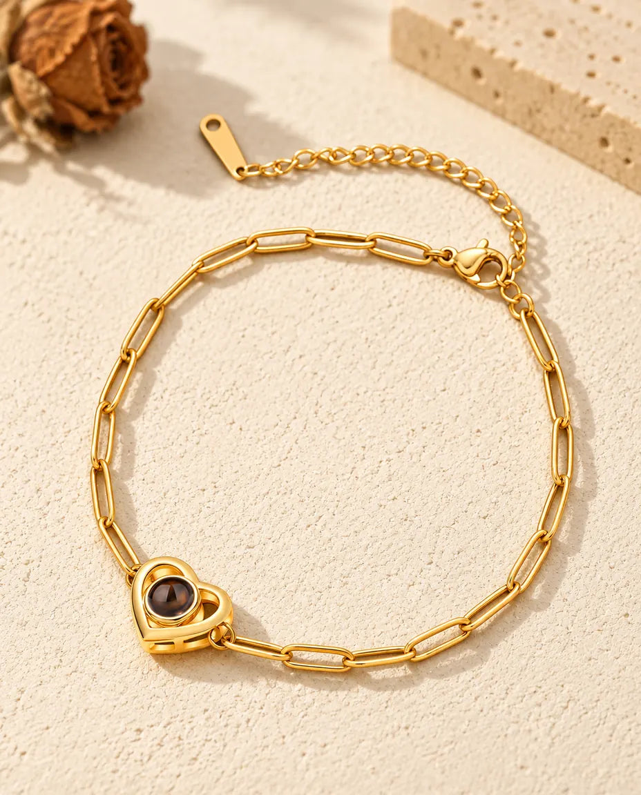 Goldfarbenes Doppelherz-Armband mit Bild im Stein auf hellem Gips