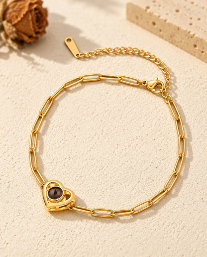 Goldfarbenes Doppelherz-Armband mit Bild im Stein auf hellem Gips