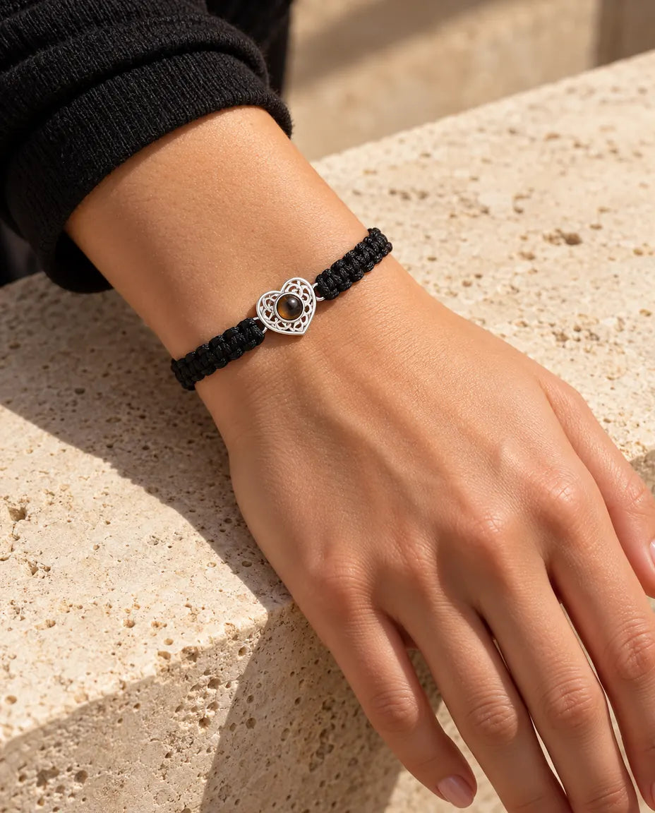 Frau trägt das Armband mit schwarzem Flechtband und silberfarbenem Herz am Handgelenk im Sonnenlicht
