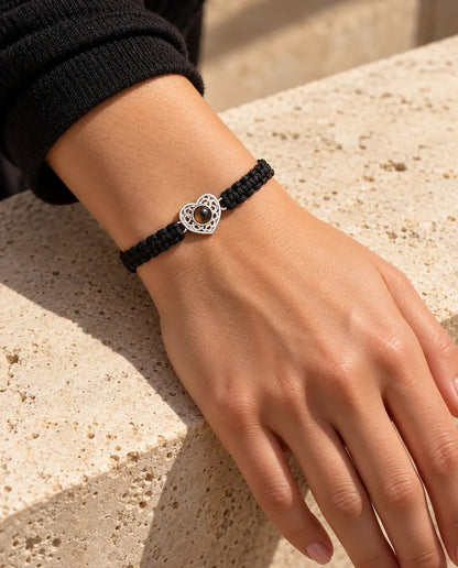 Frau trägt das Armband mit schwarzem Flechtband und silberfarbenem Herz am Handgelenk im Sonnenlicht