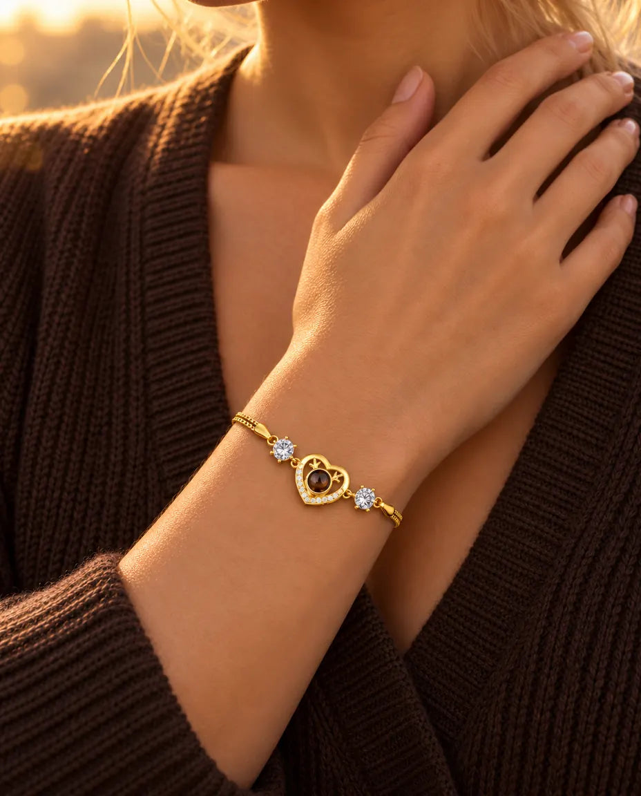Nahaufnahme des goldfarbenen Herz-Armbands mit Zirkonia am Handgelenk, die Hand ruht am Schlüsselbein