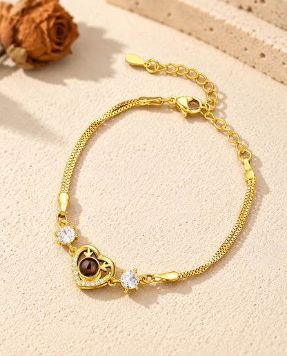 Goldfarbenes Herz-Armband mit Zirkonia, Karabinerverschluss und Verlängerungskette auf hellem Gips