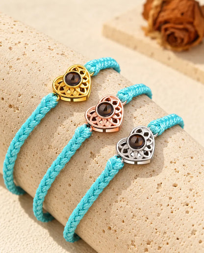 Armbänder mit schmalem blauem Flechtband und Herz in Gold, Roségold und Silber auf Travertin