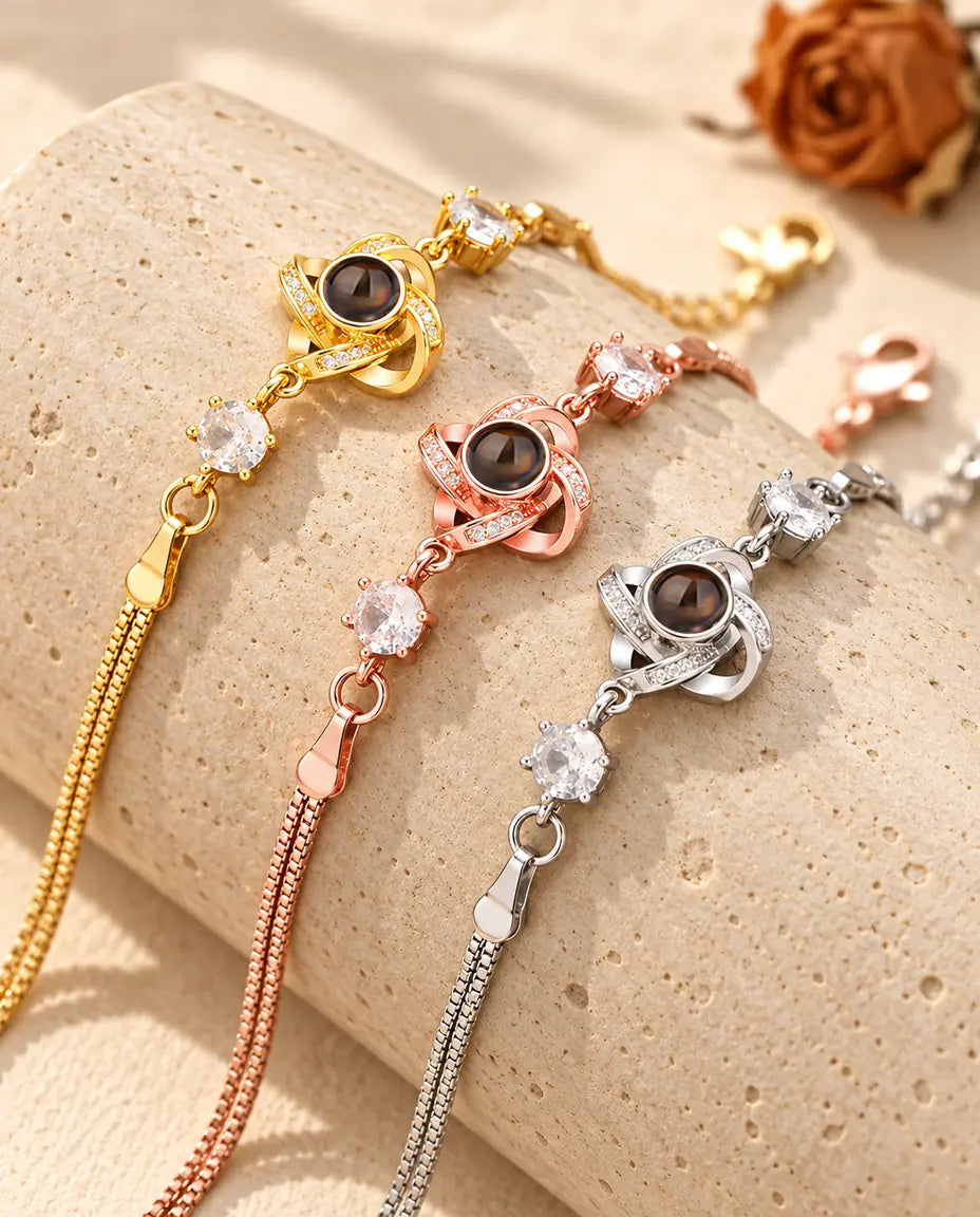 Drei Liebesknoten-Armbänder in goldfarben, roségoldfarben und silberfarben über einem Travertinblock