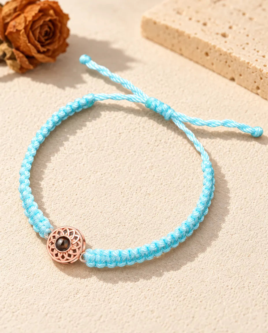Roségoldfarbener Rund-Charm an hellblauem Flechtband mit verstellbarem Schiebeknoten