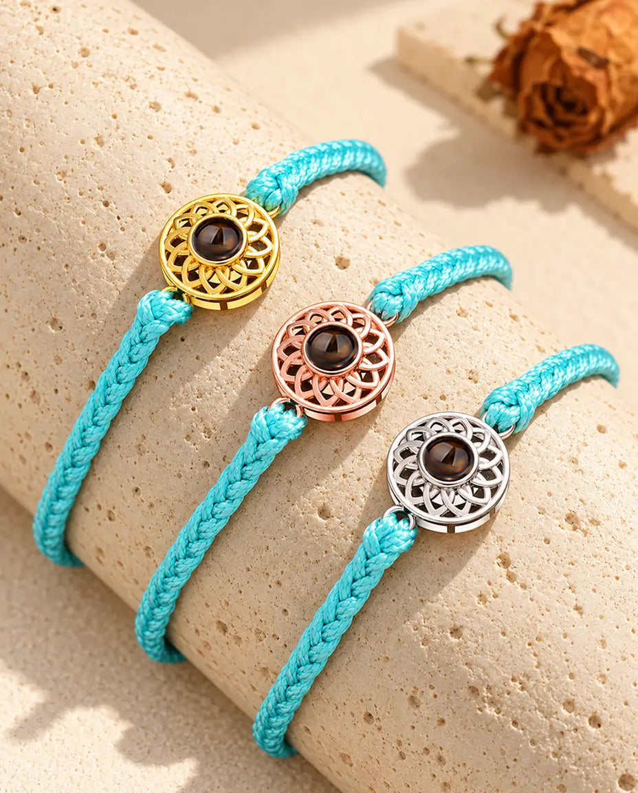 Armbänder mit schmalem blauem Flechtband und Rund-Charm in Gold, Roségold und Silber auf Travertin