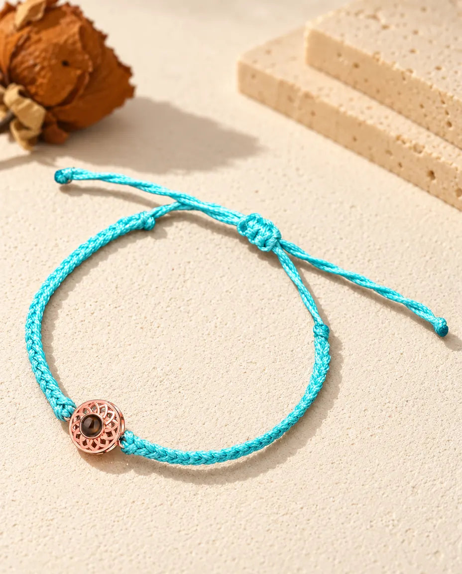 Roségoldfarbener Rund-Charm an schmalem blauem Flechtband mit verstellbarem Schiebeknoten