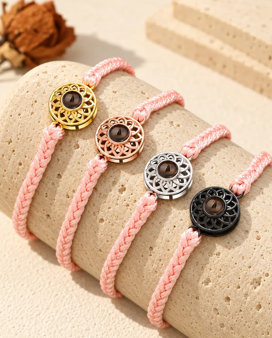 Armbänder mit schmalem rosa Flechtband und Rund-Charm in Gold, Roségold, Silber und Schwarz auf Travertin