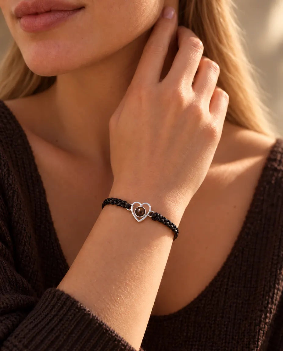 Frau mit den Fingerspitzen seitlich am Hals trägt das silberne Herz-Armband an schwarzem Band
