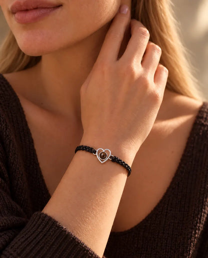 Frau mit den Fingerspitzen seitlich am Hals trägt das silberne Herz-Armband an schwarzem Band