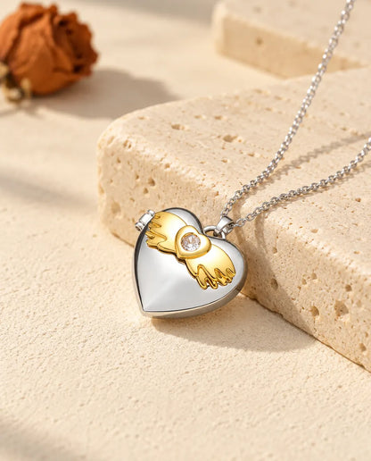 Personalisiertes Herz-Foto-Medaillon mit Engelsflügeln silberfarben mit goldfarbenen Engelsflügeln, auf einem Travertinblock