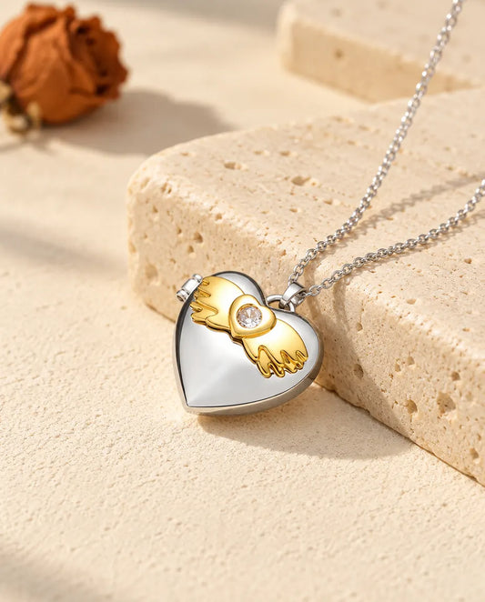 Personalisiertes Herz-Foto-Medaillon mit Engelsflügeln silberfarben mit goldfarbenen Engelsflügeln, auf einem Travertinblock
