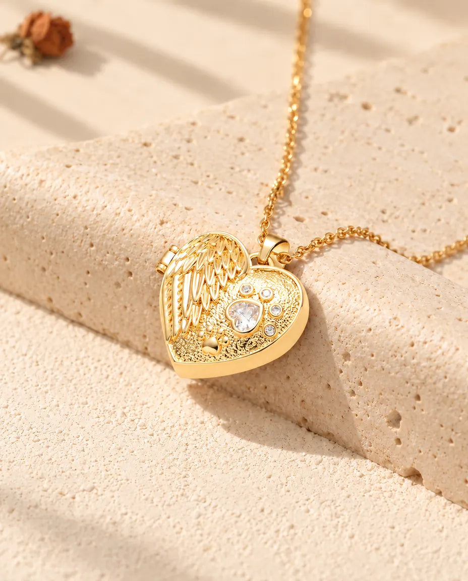 Goldfarbenes Herz-Foto-Medaillon mit Engelsflügel und Pfote als Kette an einem Travertinblock