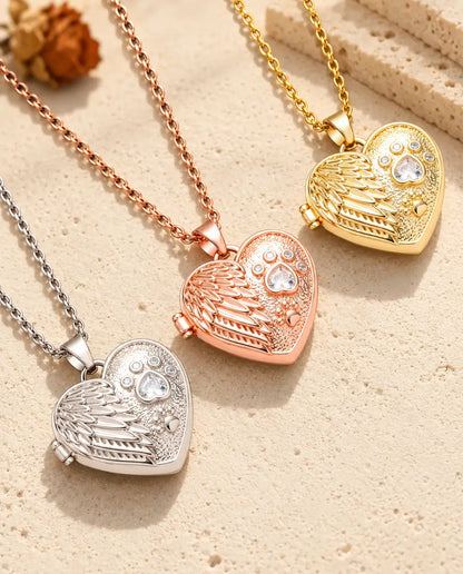 Drei Medaillons mit Engelsflügel und Pfote in Silber-, Roségold- und Goldfarben diagonal auf cremefarbenem Putz