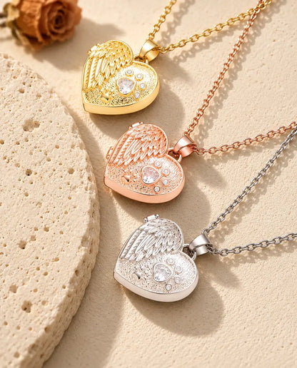 Medaillons mit Engelsflügel und Pfote in Gold-, Roségold- und Silberfarben übereinander neben einer Travertinplatte