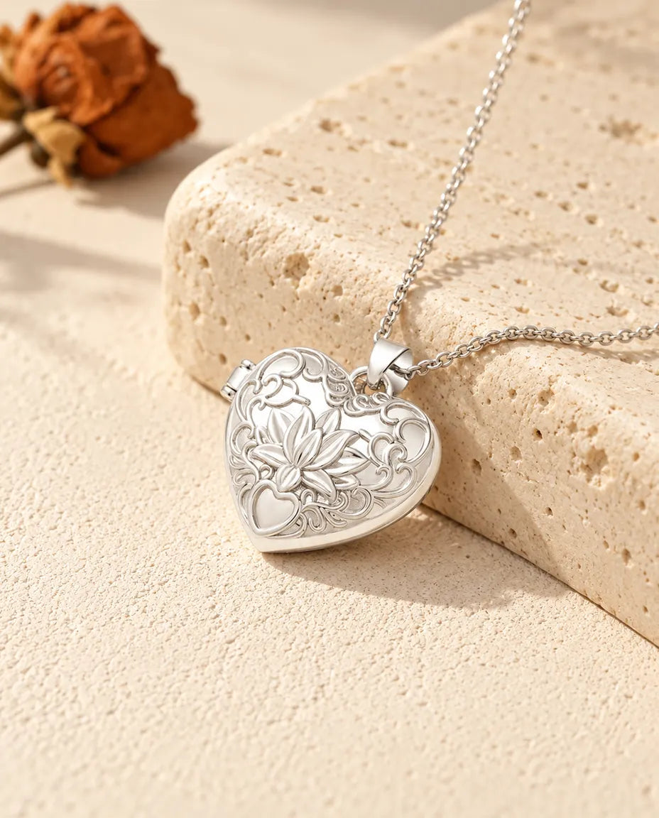 Silberfarbenes Herz-Foto-Medaillon mit Lotusblüte als personalisierte Kette, an einen Travertinblock gelehnt
