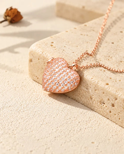 Roségoldfarbenes Pavé Herz-Foto-Medaillon auf Travertin im warmen Sonnenlicht