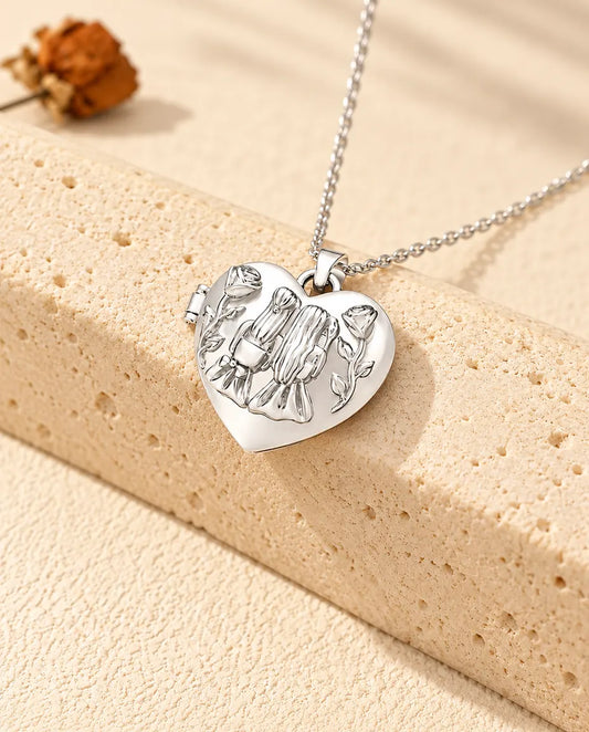 Silberfarbenes Herz-Foto-Medaillon mit zwei Schwestern als personalisierte Kette, an einen Travertinblock gelehnt