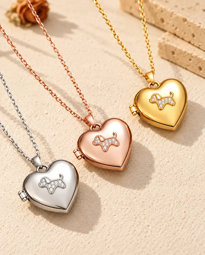 Herz-Foto-Medaillon mit Welpe in Silber-, Roségold- und Goldfarbe schräg auf cremefarbenem Putz