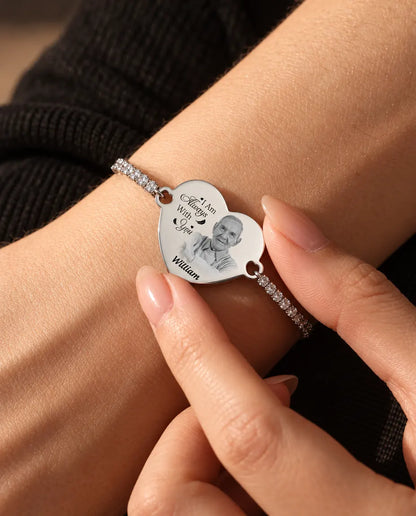 Fingerspitzen halten das gravierte Foto-Herz am silberfarbenen Tennisarmband