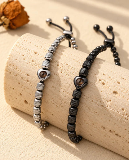 Silberfarbenes und schwarzes Perlenarmband mit Herzperle über einem Travertinblock