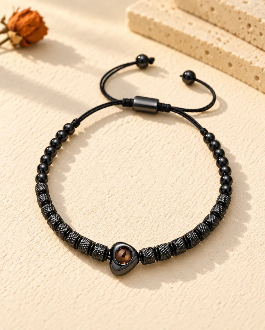 Draufsicht auf das schwarze Perlenarmband mit Herzperle auf cremefarbenem Putz
