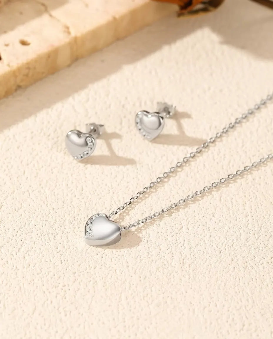 Herz Schmuckset aus 925 Sterlingsilber - Kette und Ohrringe zusammen auf heller Strukturfläche