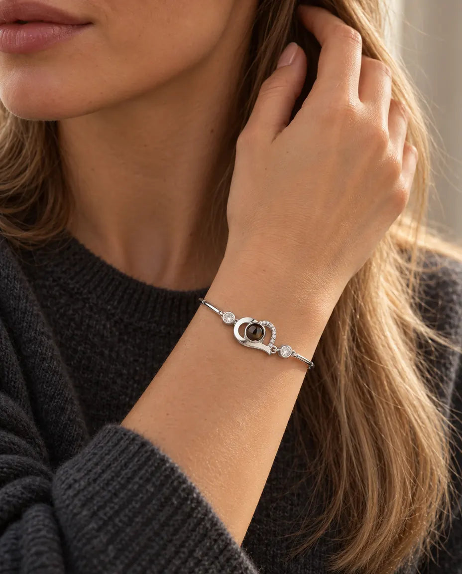 Frau mit der Hand im Haar trägt das silberfarbene Armband mit offenem Herz und Bild im Stein