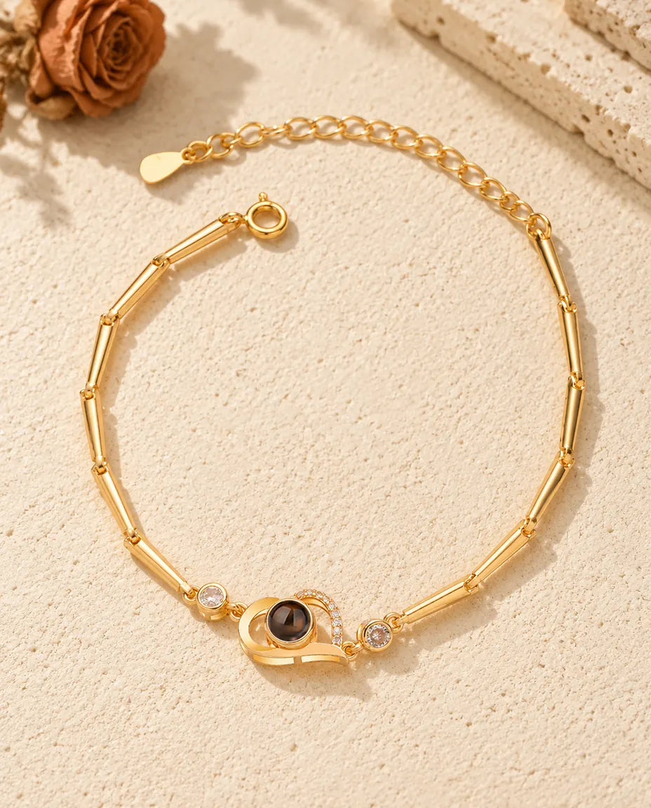 Draufsicht auf das goldfarbene Armband mit offenem Herz und Bild im Stein
