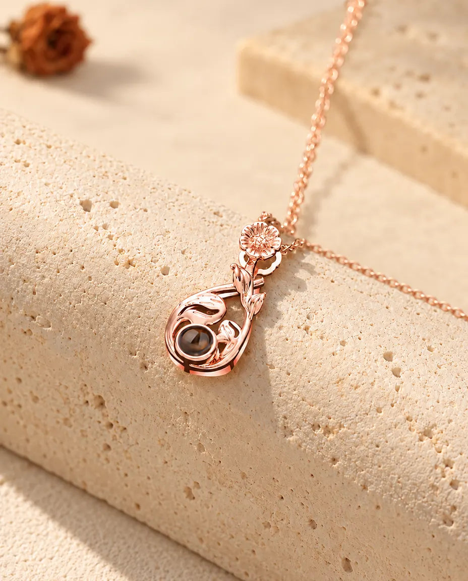 Roségoldfarbene Tropfenkette mit Gänseblümchen über einem Travertinblock