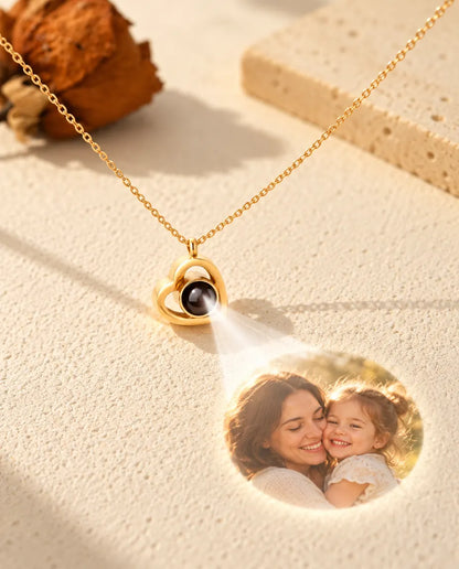 Goldfarbene Doppelherz Kette projiziert ein Foto von Mutter und Tochter auf cremefarbenen Putz