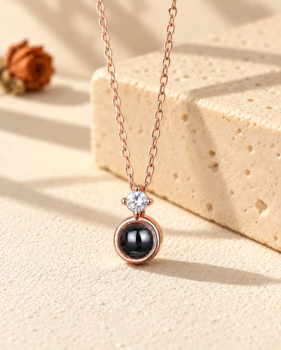 Roségoldfarbene Solitär-Kette mit Bild im Stein hängt vor einem Travertinblock