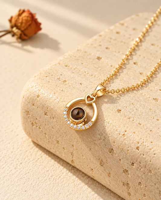 Personalisierte goldfarbene Kette mit offenem Tropfen, kleinem Herz und Bild im Stein auf Travertin