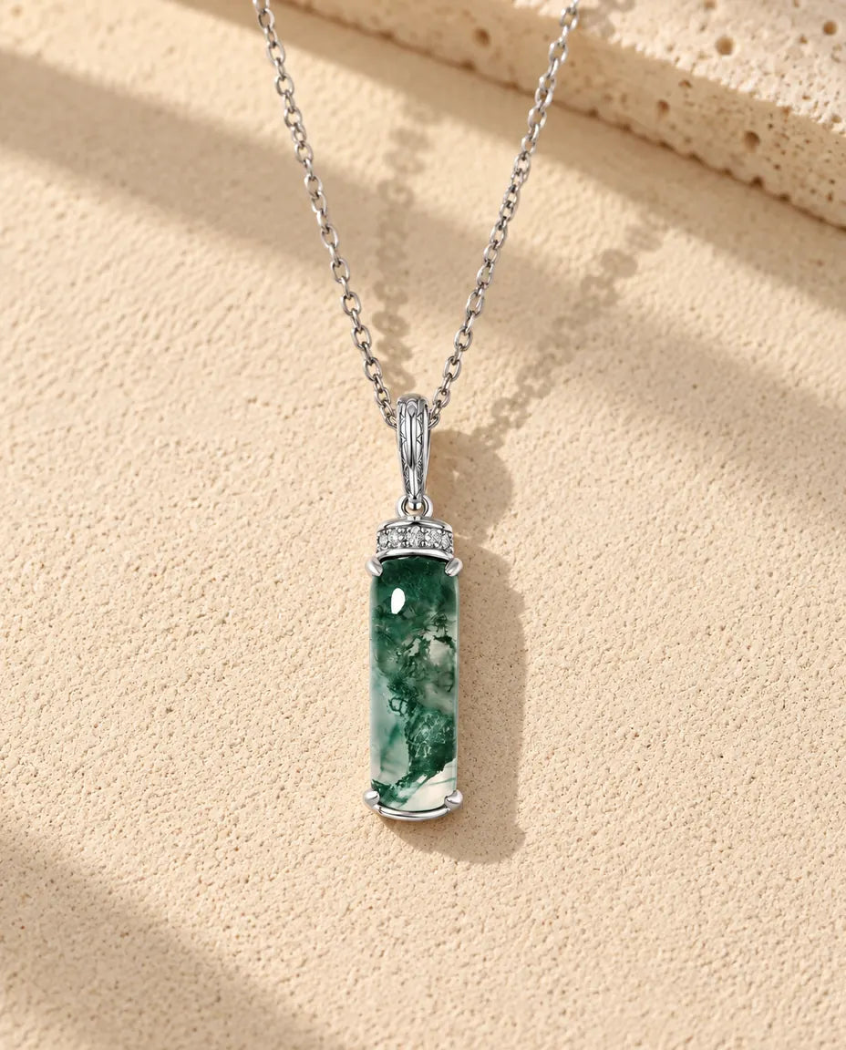 Moosachat Kette mit langem Stab aus 925 Sterlingsilber - auf heller Strukturfläche neben einem Travertinblock liegend
