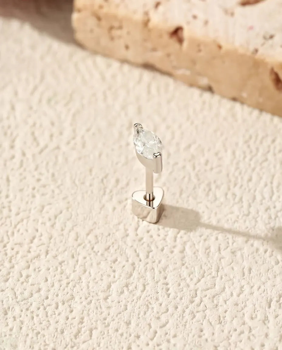 Moissanit Ohrstecker im Marquiseschliff aus 925 Sterlingsilber - aufrecht auf dem herzförmigen Verschluss stehend, auf heller Strukturfläche