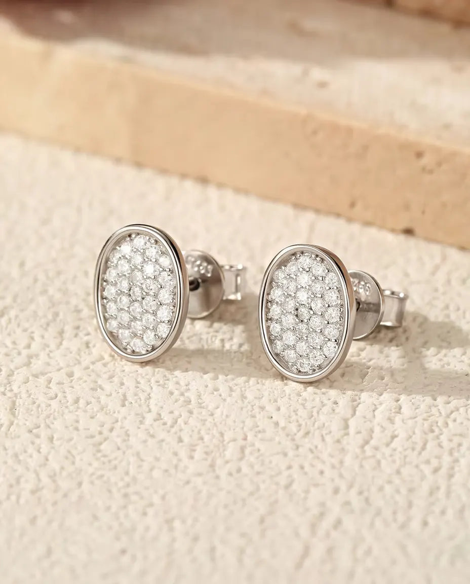 Ovale Moissanit Ohrstecker in Pavé-Fassung aus 925 Sterlingsilber - das Paar auf heller Strukturfläche