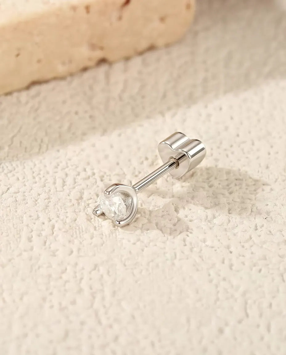 Runde Moissanit Ohrstecker mit Silberbogen aus 925 Sterlingsilber - seitlich liegend auf heller Strukturfläche, herzförmiger Verschluss auf dem Stift