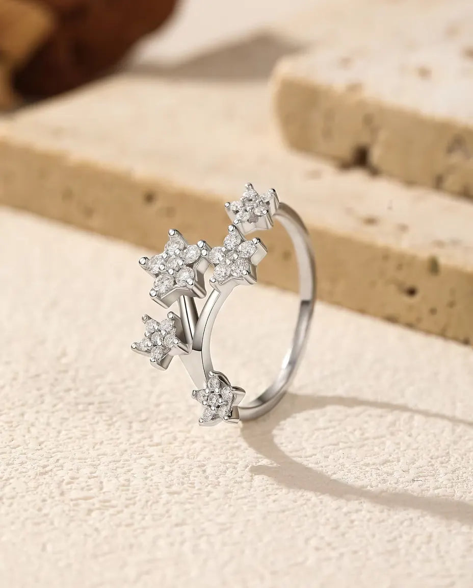 Moissanit Ring mit Sternen aus 925 Sterlingsilber - aufrecht stehend auf heller Strukturfläche