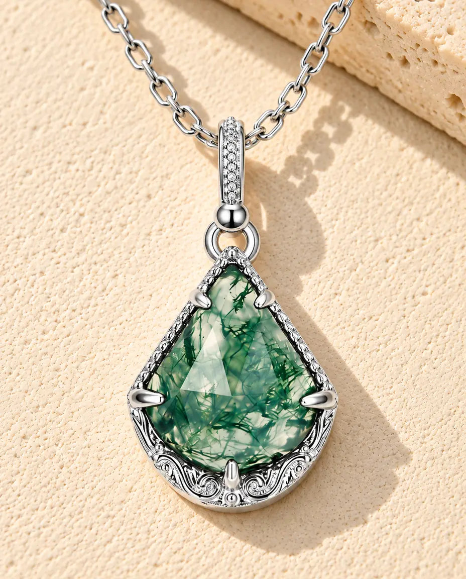 Moosachat Kette mit Drachenform aus 925 Sterlingsilber - auf heller Strukturfläche neben einem Travertinblock liegend