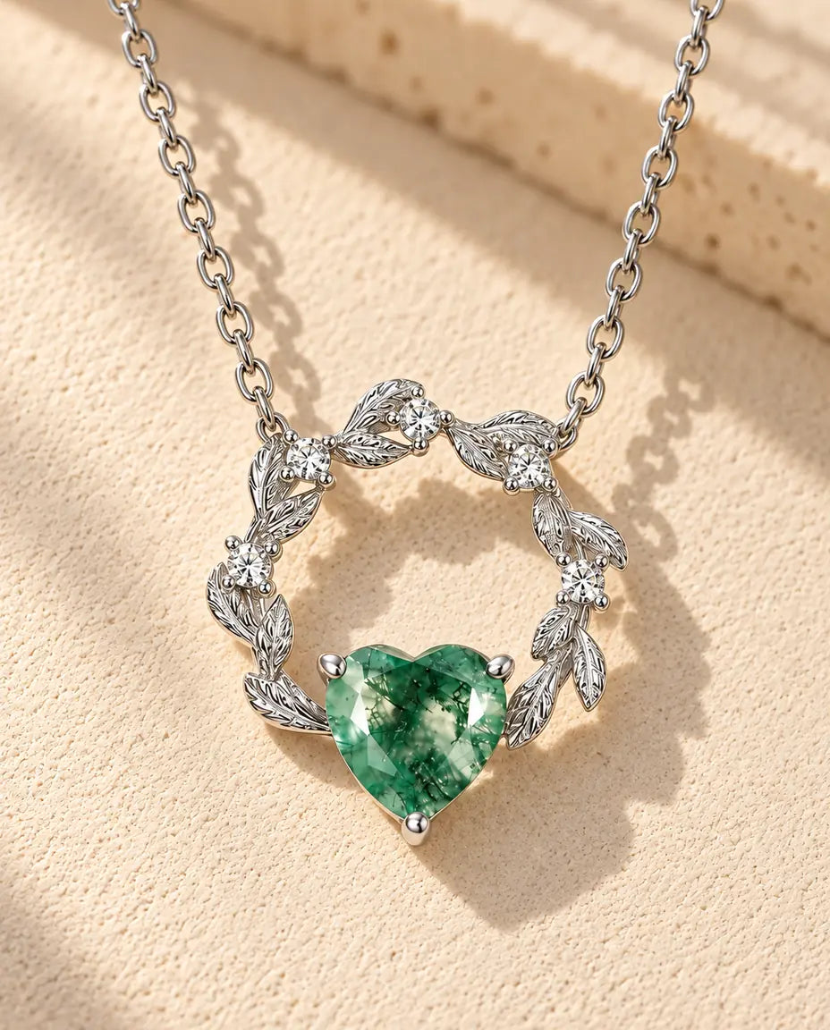 Moosachat Herz Kette aus 925 Sterlingsilber - auf heller Strukturfläche neben einem Travertinblock liegend